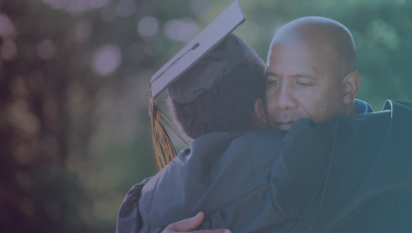 Padre e hijo abrazándose, hijo con gorra de graduación