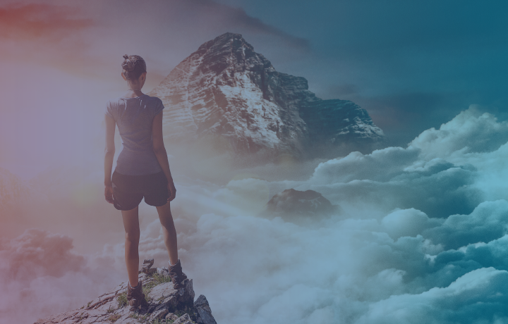 Girl standing on mountain top looking out across clouds